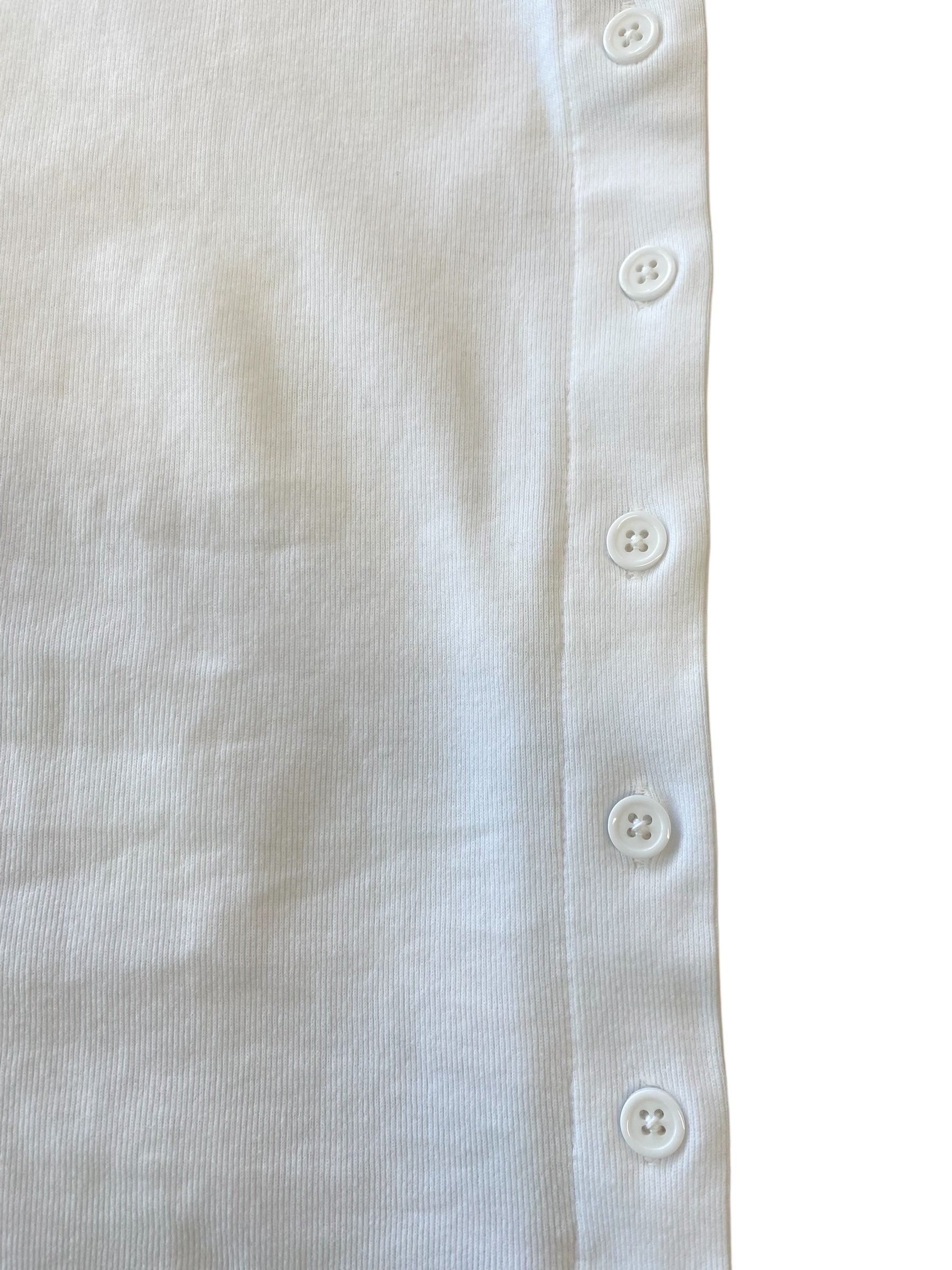 Close-up of a white fabric with button details on a plain background